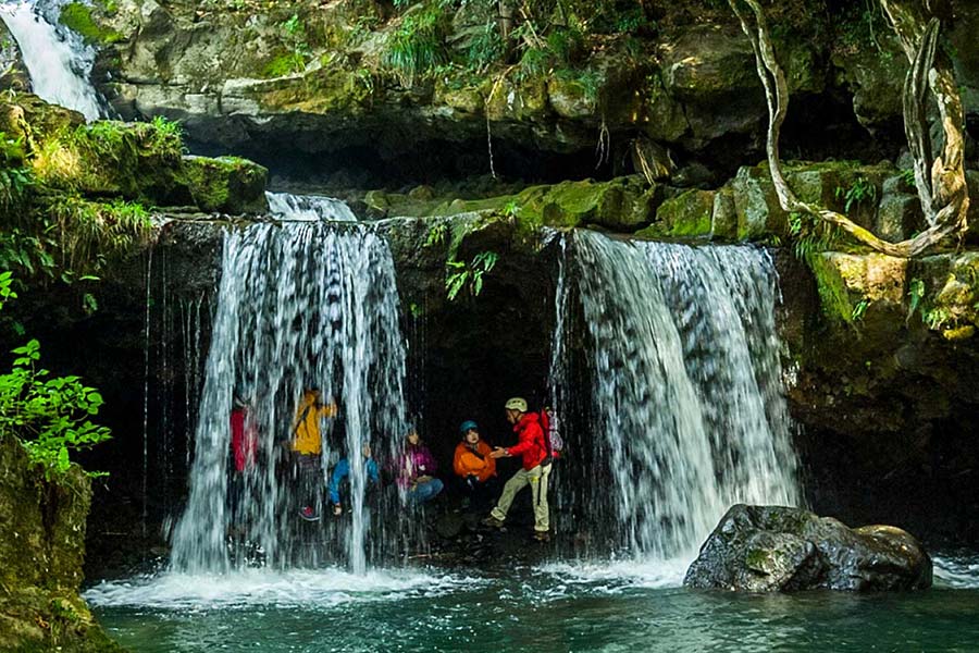 Kannabe hiking group underneath a falling waterfall